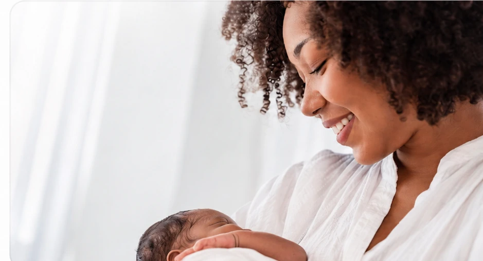 Mãe sorrindo enquanto segura seu bebê recém-nascido